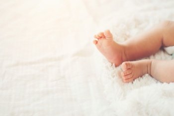 Newborn Baby legs on white bed.