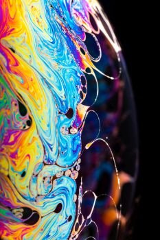 Rainbow soap bubble on a dark background. Close-up of a bubble. Rainbow soap bubble on a dark background.