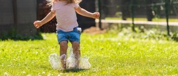 Happy child running through wet lawn splashinh water. Childhood concept. Happy child running through wet lawn splashinh water.