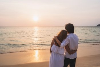 Young asian couple looking beautiful sunset on the beach, Summer vacation concept