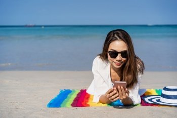 Young asian woman traveler using her smartphone at tropical sand beach, Summer vacation concept