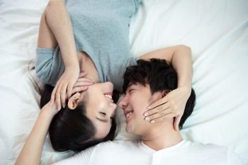 close up portrait of pretty young asian couple with happiness. asia man and woman lay on bed facing together with big smile hand touch face,love emotion with valentine concept . 