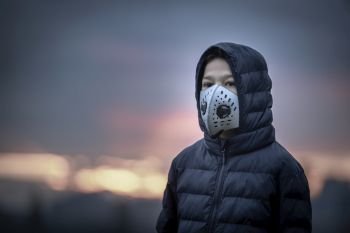 Air Pollution Concept, Young Boy with Breathing Mask, Smoke in the Background