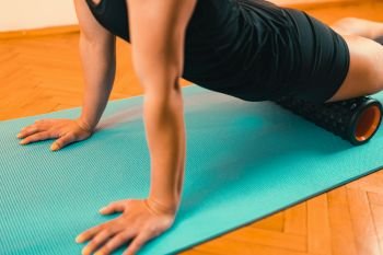 Sporty Woman Massaging Her Legs with Foam Roller . Foam Roller Quadriceps Massage 