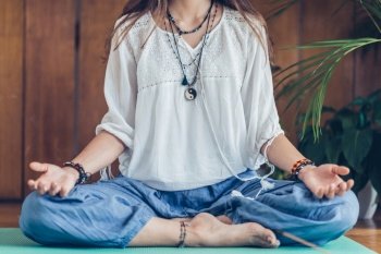 Young woman meditate while practicing Yoga. Sitting in lotus position, relaxing and enjoying incense stick after yoga class.