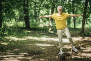 Balancing exercise outdoors. Mature woman standing on one leg, exercising balance . Balancing Exercise Outdoors