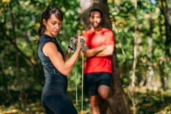 Young Couple Exercising with Elastic Resistance Bands in a Park. Young Couple Exercising with Elastic Resistance Band