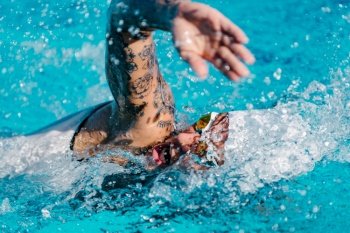 Female front crawl swimmer with tattoos  during training