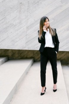 Smiling businesswoman in suit. Businesswoman talking phone outdoors. High quality photo. Smiling businesswoman in suit. Businesswoman talking phone outdoors