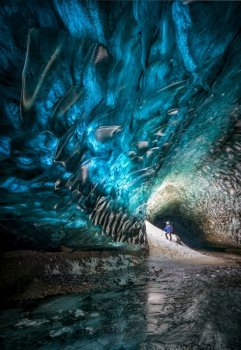 Ice cave showing a guy looking at the ice running through the holes