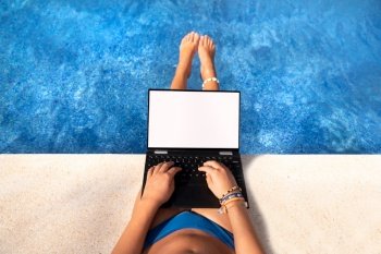 Young girl on the swimming pool looking at laptop or tablet