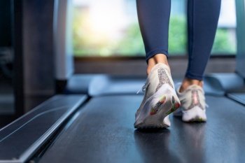 Close-up Women’s feet are running on a treadmill at the gym. Women are stretching, warming up before cardio in sport and healthy concept