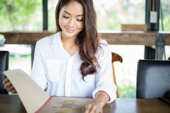 Asian woman open menu for ordering in coffee cafe and restaurant and smiling for happy time 