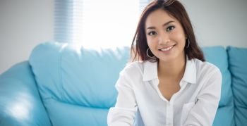 Asian women sitting relaxation on sofa and she is smiling happy at home