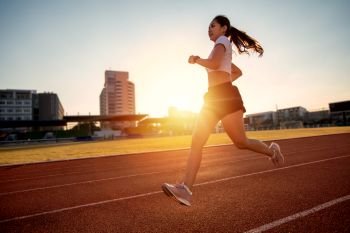Asian Young fitness woman runner running on stadium track 