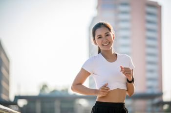 Asian Young fitness sport woman running  and smiling on city road