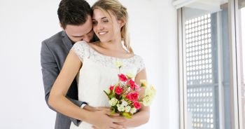 The lovers give flowers to the bride and kissed happy and couple love standing in wedding studio