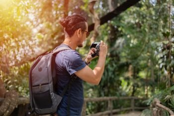 Asian men backpacks and traveler walking together and happy are taking photo on forest  ,Relax time on holiday concept travel