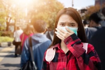 Asian Young woman walking in the city wearing protection mask on face because of air pollution, particulates and for protection flu virus, influenza, coronavirus 