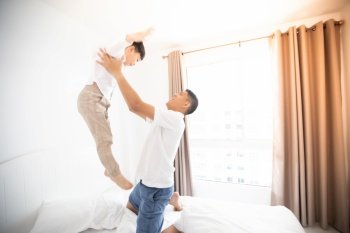 Happy Asian family with son at home on the bedroom playing and laughing 