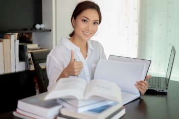 Asian women student smiling and Thump up hand sign and reading a book for relaxation and final exam
