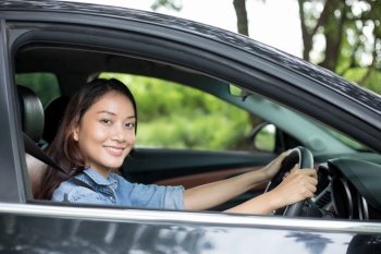 Beautiful Asian woman smiling and enjoying.driving a car on road for travel 