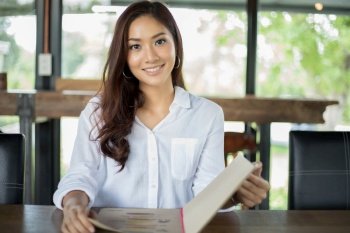Asian woman open menu for ordering in coffee cafe and restaurant and smiling for happy time 
