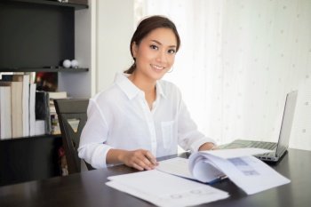beautiful Asian business women checking document and using notebook and  smiling happy for working 