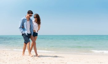 Portrait of Romantic Young couple in casual wear sun glasses walking at the beach with blue sky. Happy smiling Handsome man and Beautiful woman in love. Lover, dating, romance.