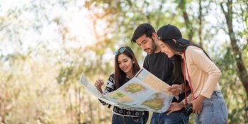 Multi-Ethnic Travelers looking at the map on travel vacations with natural background. Diversity, Friendship, People. copy space; 