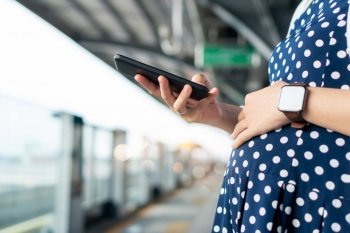 Pregnant woman enjoying internet technology while using mobile phone or smartphone during waiting commuter bus or train for traveling to work in the city. 