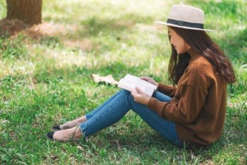 A beautiful Asian woman reading a book while sitting in the park 
