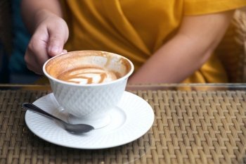 Close up image of a woman holding a white coffee mugs in cafe