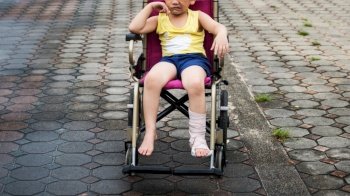 Sad painful boy with broken leg with cast sitting on wheelchair. mad and failure expression at mouth and face. Kid accident and hospital insurance concept.