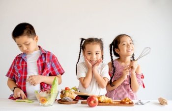 Group of little Asian girls and boy express happy and fun emotion with various food on table with white background.