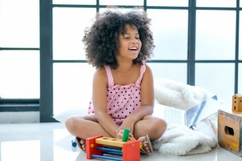 One mixed race African girl is smiling and sit on floor enjoy with the toys.