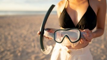Woman with equipment for snorkeling mask at the beach.