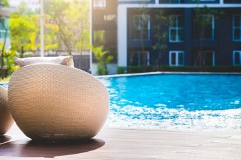 Relaxing rattan chairs with pillows beside swimming pool