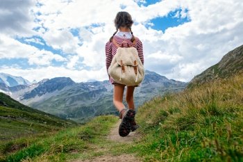 Little girl walks on mountain trail during an excursion. with the backpack.