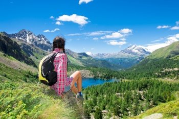 Girl resting during a trek in the mountains watching the view over a lake in the summer