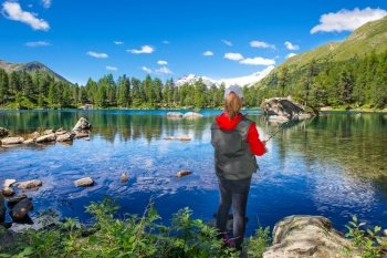 Fisher girl in an colored alpine lake in the summer