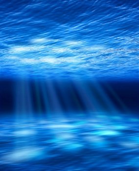 Light beams from ocean surface penetrate underwater through deep blue sea. Light beams underwater