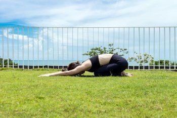 Happy Asian woman wearing black sport wear practice yoga Child pose with beautiful sea view,Feeling relax and comfortable,Healthy Concept