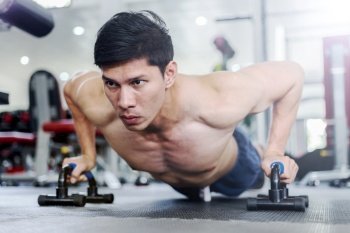 Attractive Handsome Asian young men workout with push up bar in gym focus on muscle feeling so strong and powerful,Bodybuilder concept