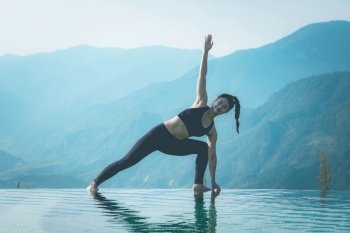 Beautiful Attractive Asian woman practice yoga Triangle pose or Utthita Trikonasana pose on the pool above the Mountain peak in the morning in front of beautiful nature views in SAPA vietnam