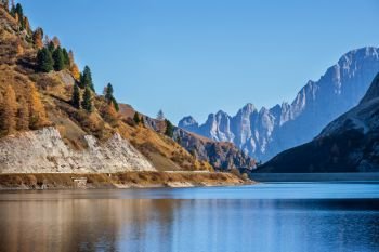 Autumn alpine Fedaia mountain Lake and Pass, Trentino, Dolomites Alps, Italy. Picturesque traveling, seasonal and nature beauty concept scene.