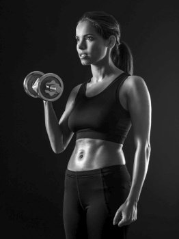 Beautiful woman exercising her bicep muscles with a dumbbell.