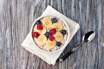 prepared oatmeal with fruits and berries on a wooden table. prepared oatmeal with fruits and berries