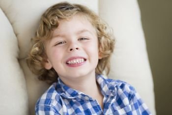 Cute Blonde Boy Smiling for Portrait Sitting in Chair.