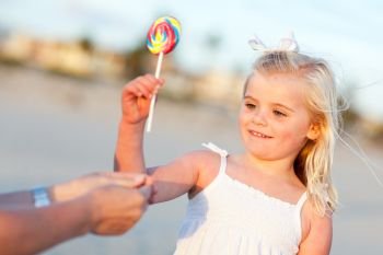 Adorable Little Girl Picking out Lollipop from Mom at the Beach.